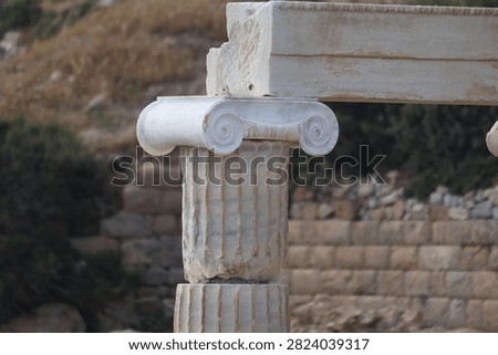 Close-up of an ancient Ionic marble column capital with scroll volutes and architrave block at the archaeological site of Knidos in Turkey.