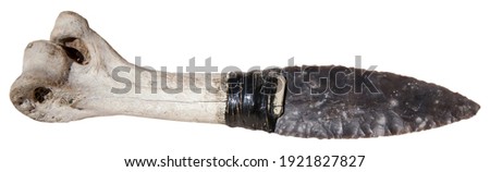 Close-up of ancient stone dagger with bone handle isolated on white background, prehistoric handmade knife and archaeological artifact from early human culture and Stone Age history.