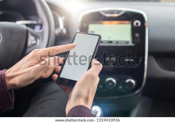 Closeup angled view shot\
of a male hand holding smart phone while sitting in a car. It\'s the\
daily traffic