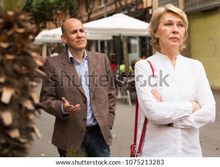 closeup of angry retiree blond woman being sad with man outdoors