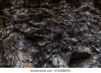 A close-up of an angular rock formation featuring sharply defined layers and fractured geological structures. The rugged stone surfaces display mineral textures and natural weathering, highlighting the complex patterns formed by geological forces over time.