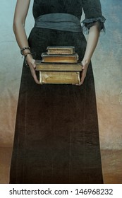 closeup of antique torn books with a hands of a young woman held against black dress on a grunge textured background 