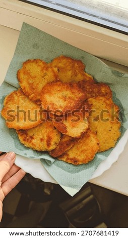 A close-up, appetizing studio shot of freshly made Deruny (potato fritters), a staple of Ukrainian and Eastern European cuisine. The golden-brown pancakes are stacked or arranged on a rustic