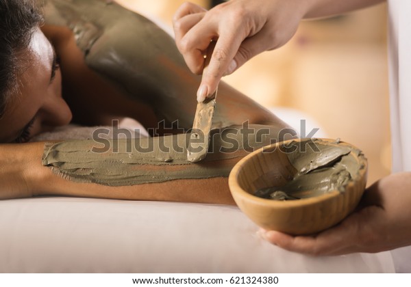 Closeup of applying mud mask with hands of\
professional therapist.