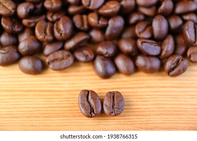 Closeup of Arabica VS Robusta Roasted Coffee Beans with Blurry Coffee Beans Pile in the Backdrop
