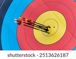 Closeup of archery target with six arrows in yellow gold hitting bulls eye successfully scoring