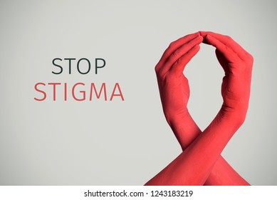 closeup of the arms of two men painted red forming a red ribbon for the HIV/AIDS awareness and the text stop stigma against an off-white background