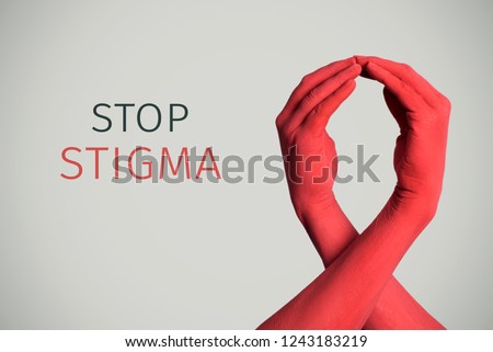 closeup of the arms of two men painted red forming a red ribbon for the HIV/AIDS awareness and the text stop stigma against an off-white background