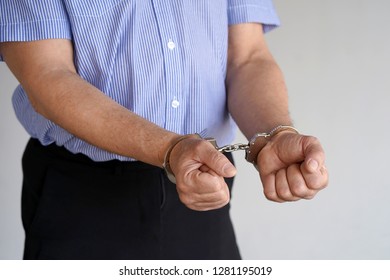 Close-up. Arrested Elderly Man Handcuffed Hands Isolated On Gray Background. Prisoner Or Arrested Terrorist, Close-up Of Hands In Handcuffs.