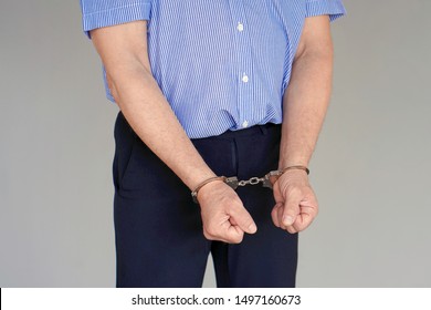 Close-up. Arrested Elderly Man Handcuffed Hands Isolated On Gray Background. Prisoner Or Arrested Terrorist, Close-up Of Hands In Handcuffs.                               