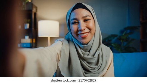 Close-up Asia muslim woman in hijab with casual sitting on sofa use smartphone video conference selfie look at camera with boyfriend on living room in home at night. Girl Islam lifestyle concept. - Powered by Shutterstock