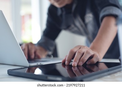 Closeup Of Asian Business Man Working On Laptop Computer And Using Digital Tablet Pc On Table At Home Office. Freelancer Working  From Home, Wireless Technology, Paperless Office