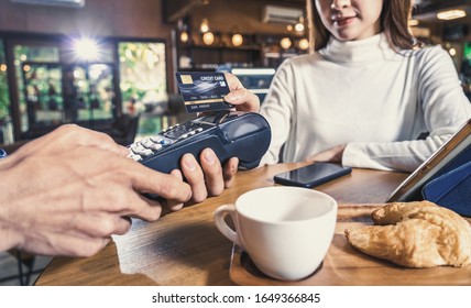 Closeup Asian customer woman paying with credit card via contactless nfs technology to Asian Small Coffee shop owner at the female table in cafe,Small business owner and startup in coffee shop concept