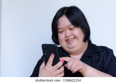 Close-up of an Asian girl with a disability. Down syndrome children. Play phone and smile happy on a white background Concept: Down Syndrome
