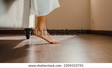 Close-up Asian girl foot step down on bed with white pajamas wake up walk to open curtain on window fresh peaceful morning light empty floor in bedroom at home. Female morning lifestyle concept.