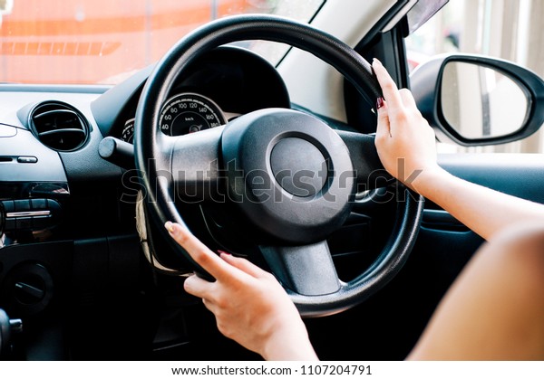 Close-up of Asian girls\
doing hand gestures while driving a car, catching the steering\
wheel while driving.