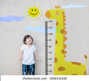 Closeup Asian Kid Stand For Measure Height And Look At Cute Giraffe Cartoon At The Marble Stone Wall Textured Background