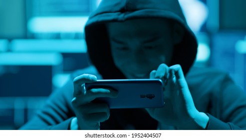 closeup of asian male hacker using cellphone to steal mobile game