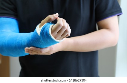 Closeup of asian man's arm with long arm plaster, fiberglass cast therapy cover by blue elastic bandage after sport accident. Appropriate treatment in western medicine. - Shutterstock ID 1418629304