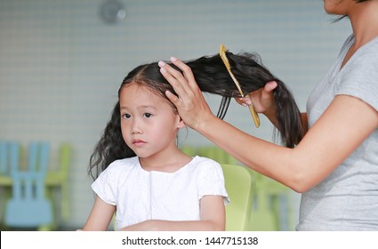 Close-up Asian Mom Combing Her Daughter Hair At Home.