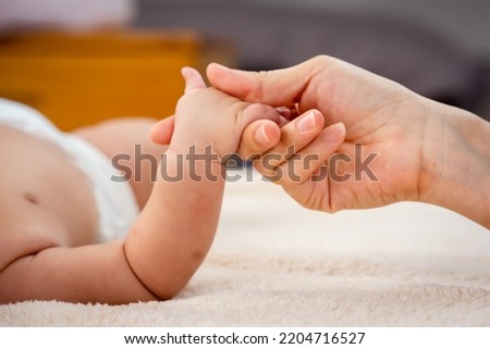 Close-up of Asian mother's hand She held her lovely daughter's hand with love and care. newborn baby sleeping deep in bed sleep well in bed at home