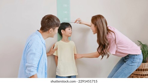 closeup asian parents help their boy doing height measurement with his growing up and taller