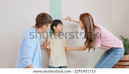 closeup asian parents help their boy doing height measurement with his growing up and taller