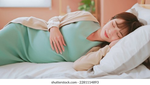 closeup asian pregnant woman laying on the bed happily taking a rest and enjoying motherhood moment with smile - Powered by Shutterstock