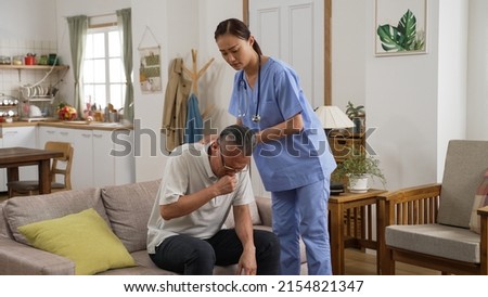 closeup of asian senior man is coughing while home attendant is patting on his back to help loose the sputum from lung in living room at home. domiciliary care concept