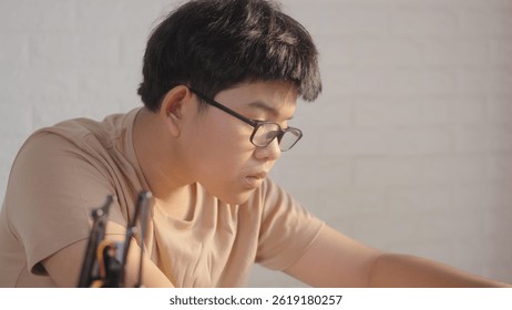 Close-up of Asian teenage boy coding a robotics project on a laptop at home, concept of STEM education, robotics, and coding for young engineers. - Powered by Shutterstock - Get 15% off with code: PIKWIZARD15
