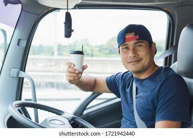 Close-up An Asian Truck Driver Is Driving And Smiling Happily. He Has A White Coffee Cup In His Hand.