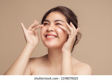 Closeup Asian woman with beauty face touching healthy facial skin portrait. Beautiful smiling Asian female model with natural makeup touching glowing hydrated skin on beige background. - Shutterstock ID 2198070025