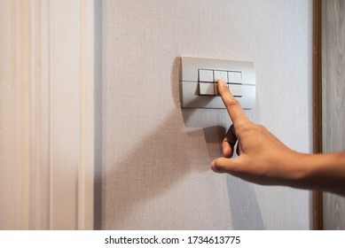 Closeup Of Asian Woman Finger Is Turning Off On Grey Light Switch Over Textile Texture Wall In The Hotel. Copy Space. Energy Saving.