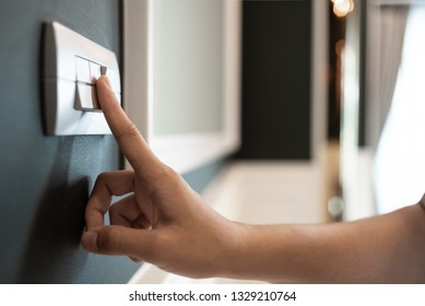 Closeup Of Asian Woman Hand Is Turning On Or Off On Grey Light Switch Over Green Wall In The Hotel. Copy Space. Energy Saving.