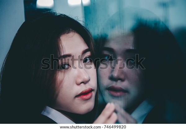 Closeup asian woman sad from love at mirror with\
reflection in a raining day vintage style,heartbreak woman\
concept,stress girl