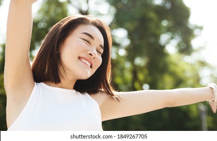 Close-up of asian woman stretching hands up and smiling, walking in park, looking carefree and happy. Modern girl breathing fresh air on a walk, look free and joyful. - Powered by Shutterstock