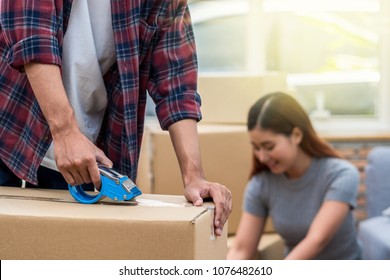 Closeup Asian Young Couple Packing The Big Cardboard Box For Moving In New Home, Moving And House Hunting Concept,