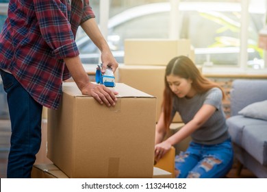 Closeup Asian Young Couple Packing The Big Cardboard Box For Moving In New House, Moving And House Hunting Concept,