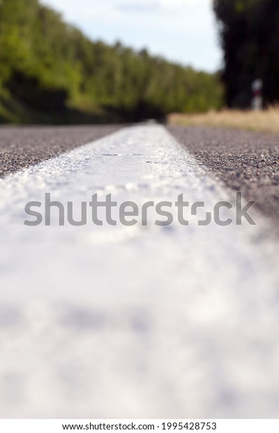 close-up of an asphalt road with white road\
markings painted on it, a road for cars and other types of\
transport, road markings regulate\
traffic
