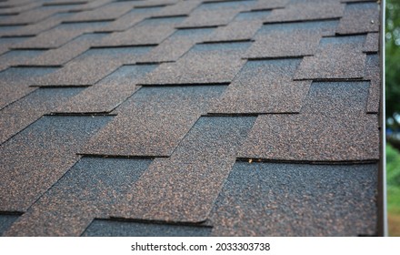 A Close-up Of Asphalt Shingles Installation On The Edge Of The Roof. Brown Architectural Asphalt Shingles Background, Texture.