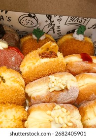A close-up of an assorted box of fluffy, delectable donuts with various creative toppings and fillings