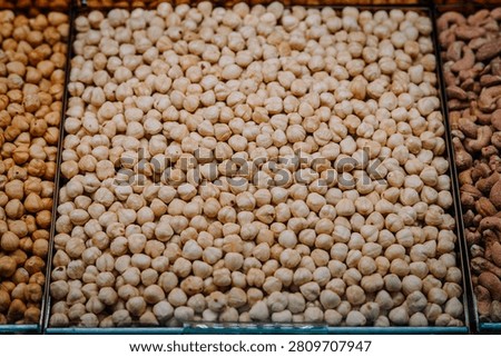Close-up of assorted nuts including roasted chickpeas, cashews, and peanuts arranged in a market display, showcasing distinct textures and colors