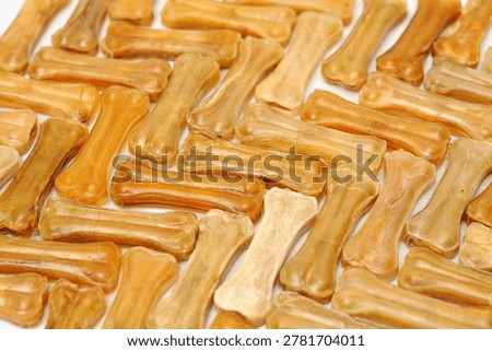 Closeup of assorted rawhide dog bones and chew treats scattered on a white background.
