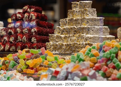 Close-up of assorted Turkish sweets, featuring nougat with pistachios, vibrant Turkish delight cubes, and red nut rolls in a showcase.