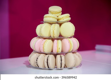 Closeup assortment of lots of multicolored tasty macarons on tier circle cake tower display. Colorful macarons on pyramid-shaped plastic stand on many visible levels