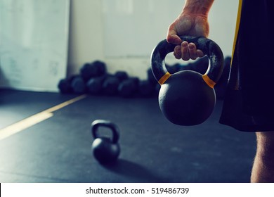 Close-up of athletic man holding kettlebell weight at gym