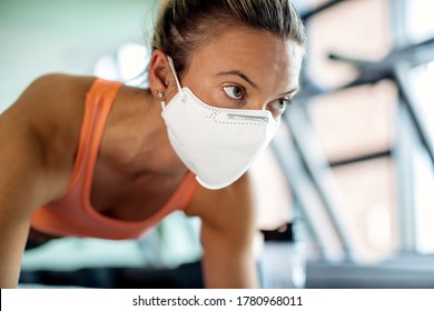 Close-up of athletic woman wearing protective face mask while exercising in a gym during coronavirus epidemic. 