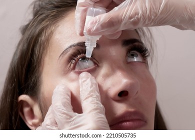 Close-up attentive optometrist dripping eye drops into the patient's eyes. Optometrist during an examination in a modern clinic - Powered by Shutterstock