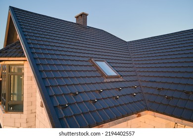 Closeup of attic window on house roof top covered with ceramic shingles. Tiled covering of building