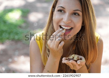 Close-up of attractive healthy woman eating Brazil nuts in the park
